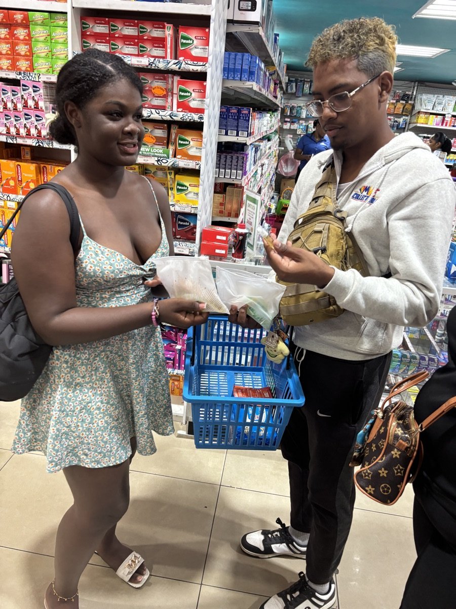 A Summit rep handing product samples to a shopper holding a basket in a pharmacy aisle